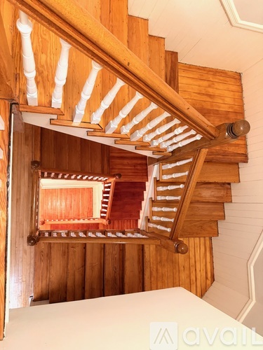 A wooden staircase with white balusters and a wooden handrail.