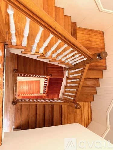 A wooden staircase with white balusters and a wooden handrail.