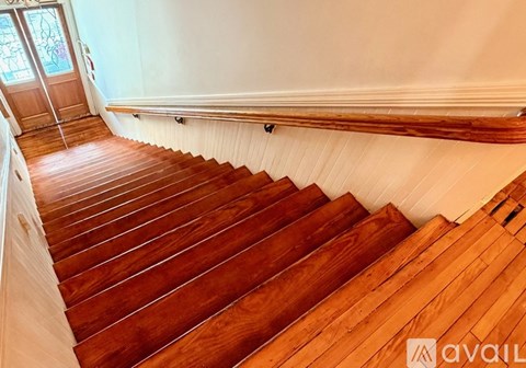A wooden staircase with a white wall on the side.