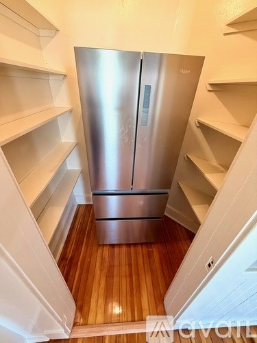 A stainless steel refrigerator in a narrow kitchen space.