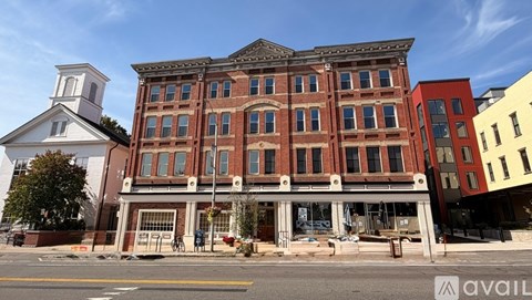 A large red brick building with a white tower to the left and a smaller building to the right.