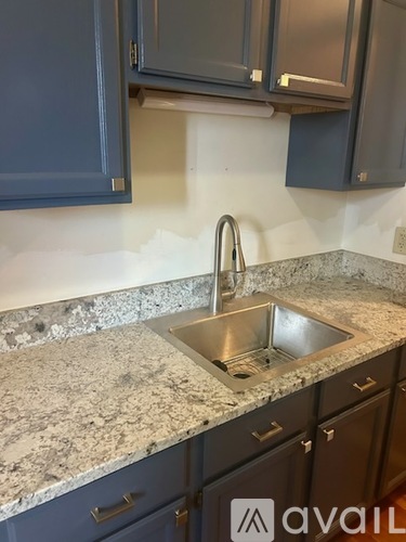 A kitchen with a granite countertop and a stainless steel sink.