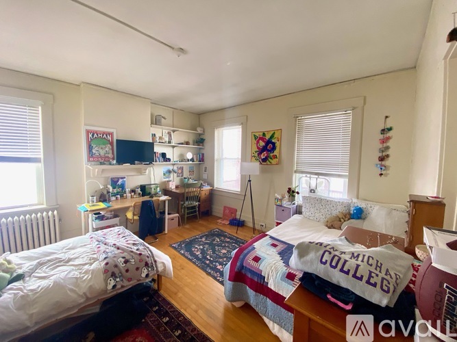 A bedroom with a bed in the center and a desk with a chair in the corner.