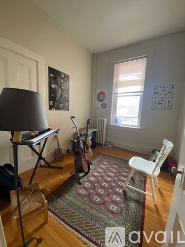 A room with a guitar, a chair, and a lamp.