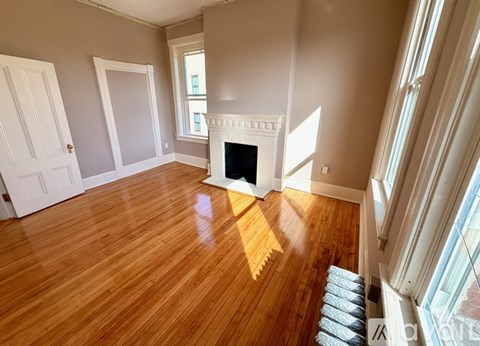 A room with a fireplace and wood flooring.