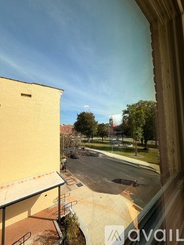 A view from a window looking out at a street with a yellow building on the left.
