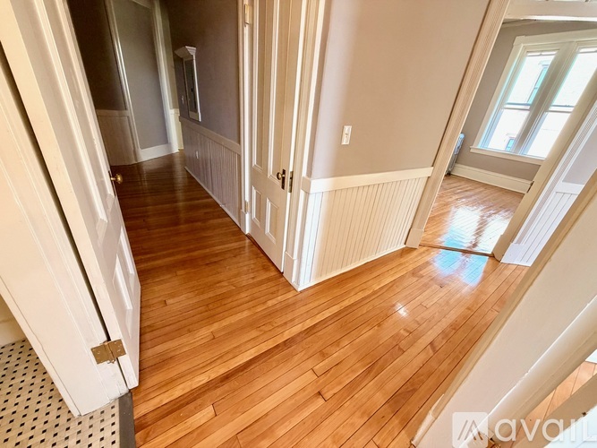 A hallway with wood floors and white walls.