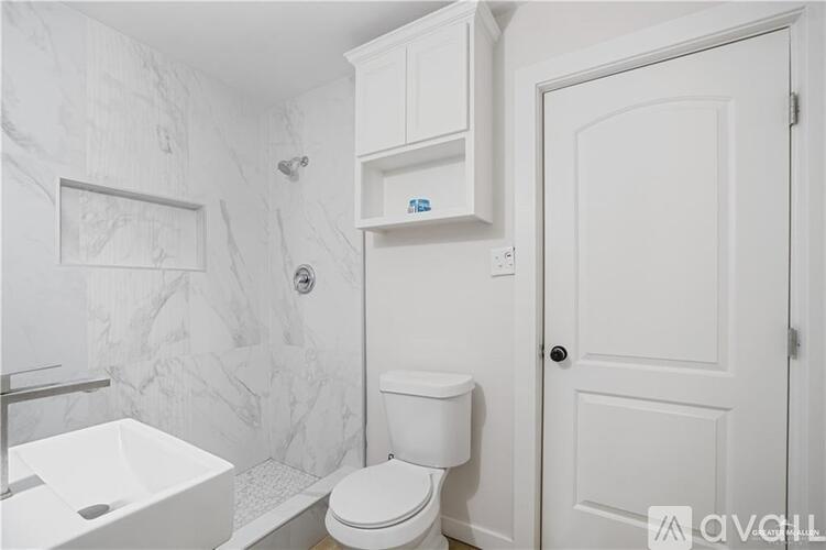 A white toilet sits next to a white sink in a bathroom.