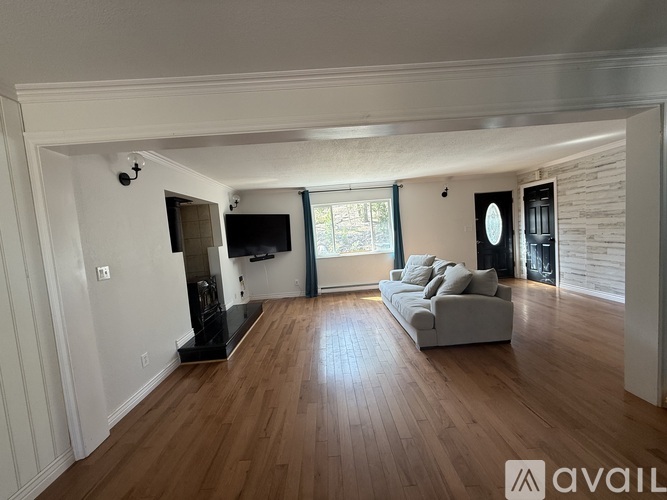 A living room with a grey couch and wooden floors.