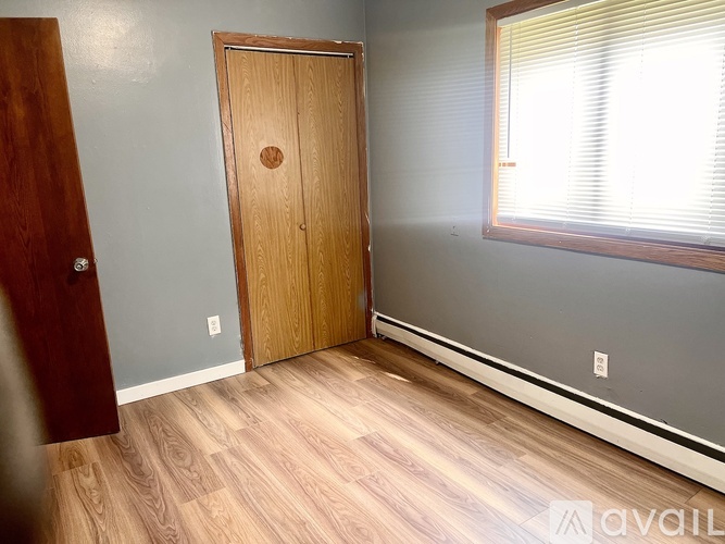 A room with a wooden door and a window with blinds.