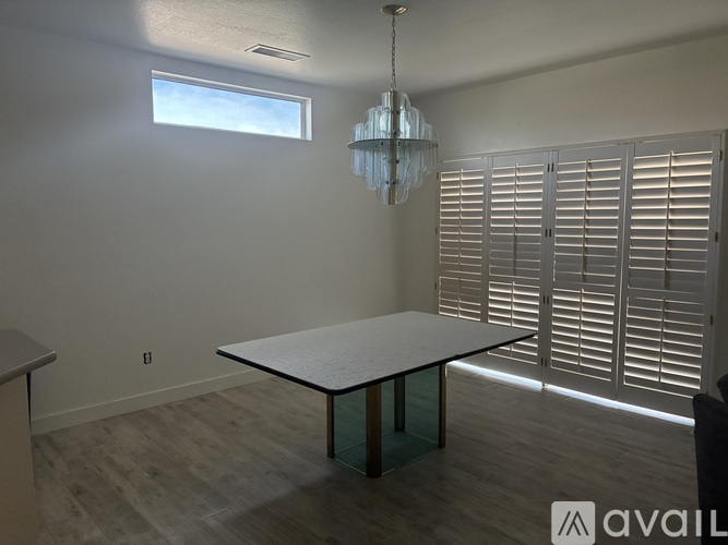 A room with a table, chairs, and a chandelier.