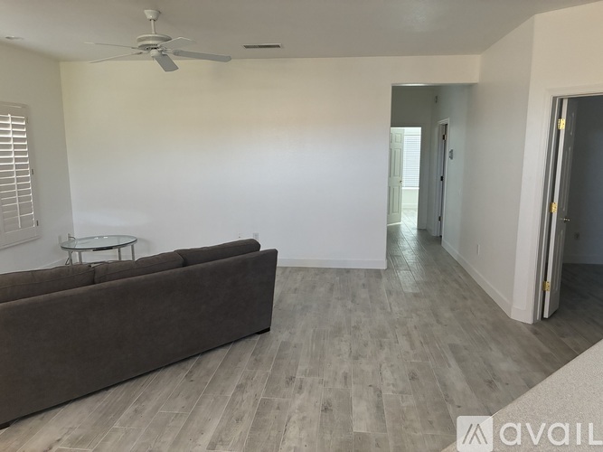 A living room with a brown couch and a ceiling fan.