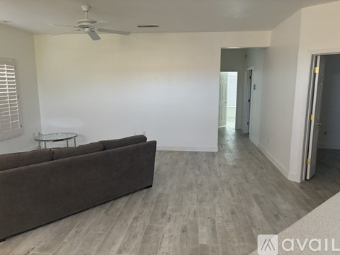 A living room with a brown couch and a ceiling fan.