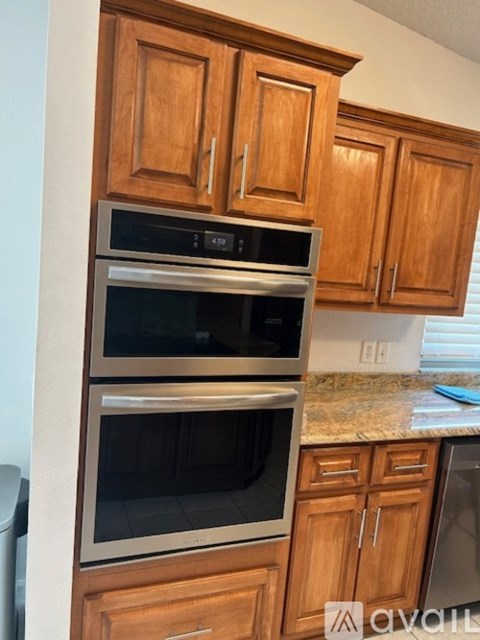 A kitchen with wooden cabinets and a double oven.