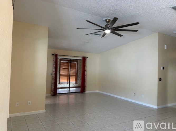 A spacious room with a ceiling fan and a sliding glass door.