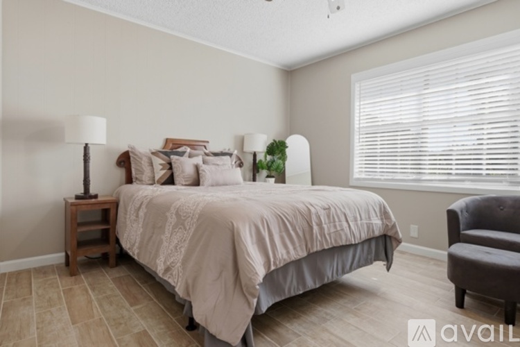 A bedroom with a bed, chair, and window.