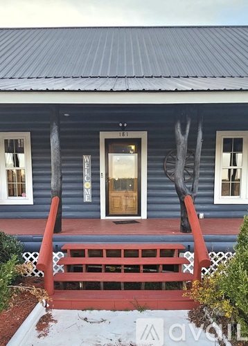 A blue house with a wooden door and a red railing.