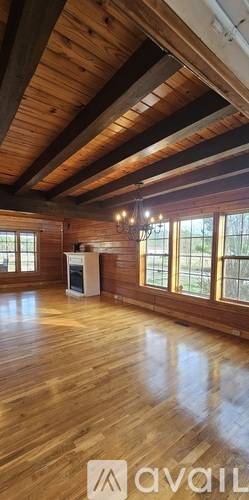 A spacious room with wooden floors and a high ceiling with exposed beams.