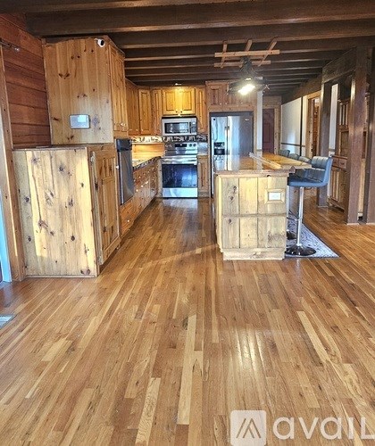 A wooden kitchen with a stove top oven and a refrigerator.