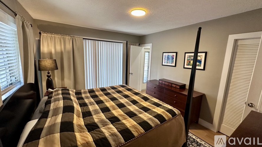 A bedroom with a checkered bedspread and a lamp on a side table.