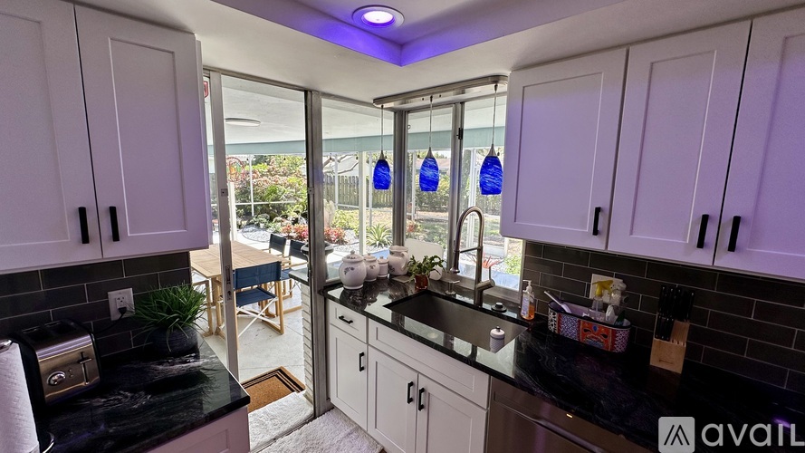 A kitchen with white cabinets and black countertops is shown.