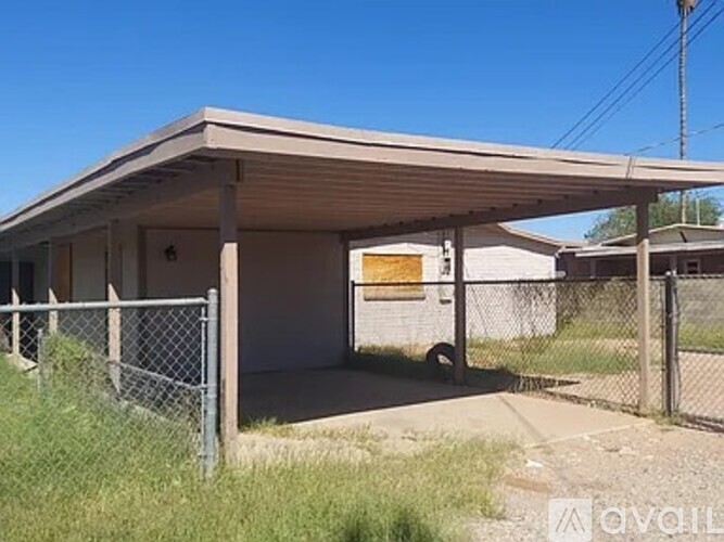 A small, single-story building with a fenced yard in front.