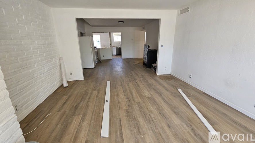 A spacious room with wooden flooring and white walls.