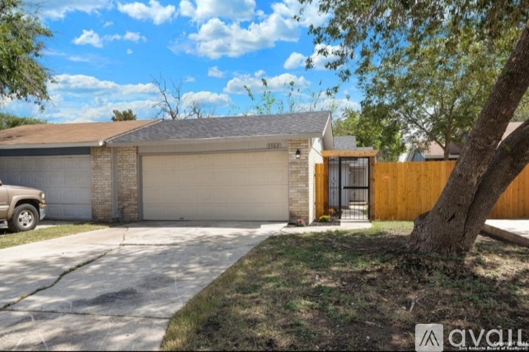 A house with a garage and a tree in front.