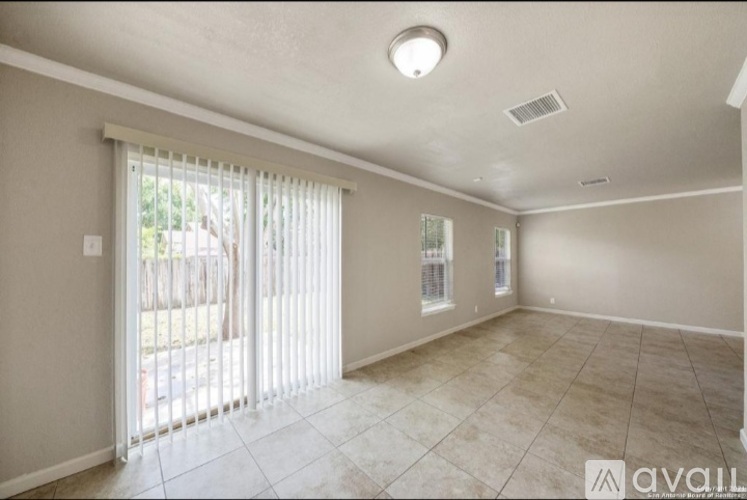 A spacious room with a sliding glass door leading to a backyard.
