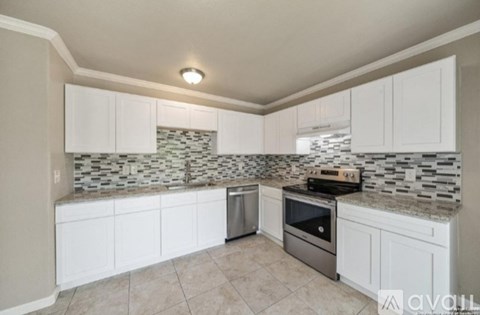 A kitchen with white cabinets and a tiled backsplash.
