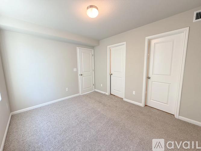 A room with a carpeted floor and three doors.