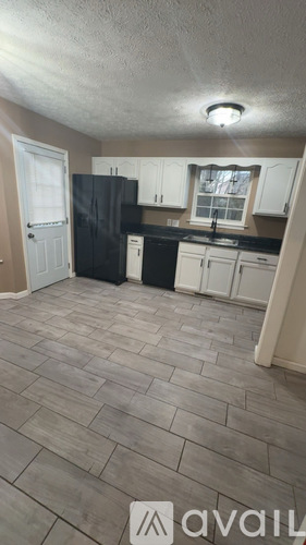 A kitchen with black appliances and white cabinets.