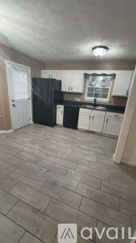 A kitchen with black appliances and white cabinets.