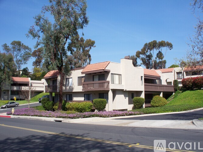 A building with a red roof is surrounded by greenery.