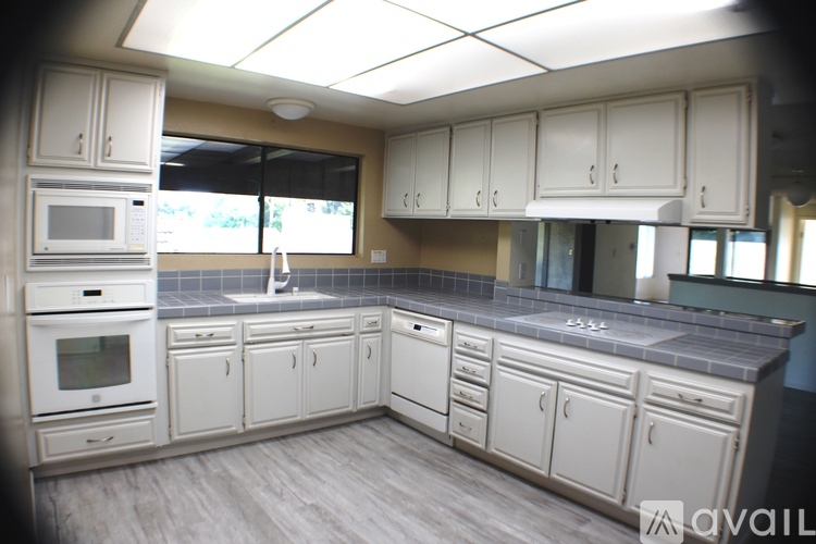 A kitchen with white cabinets and a grey counter top.