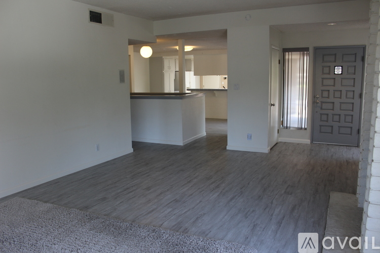 A spacious living room with a grey carpet and wooden flooring.