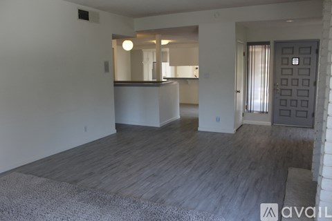 A spacious living room with a grey carpet and wooden flooring.