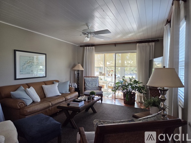 A living room with a brown couch, a coffee table, and a ceiling fan.