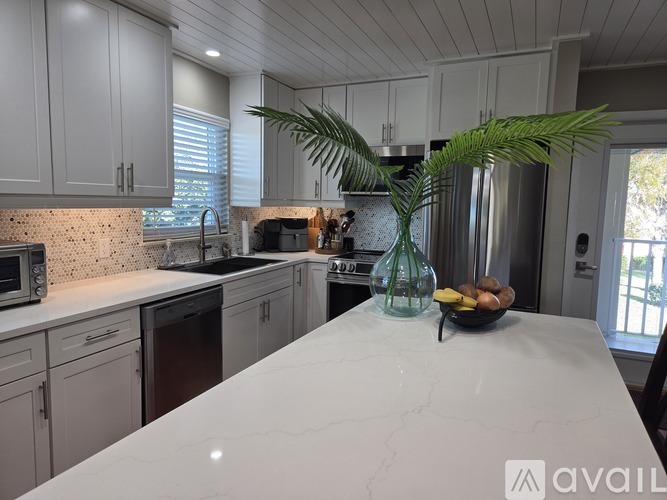 A kitchen with a white countertop and a bowl of fruit on it.