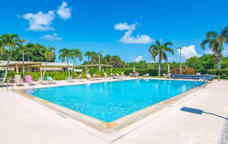 A large swimming pool surrounded by palm trees and lounge chairs.
