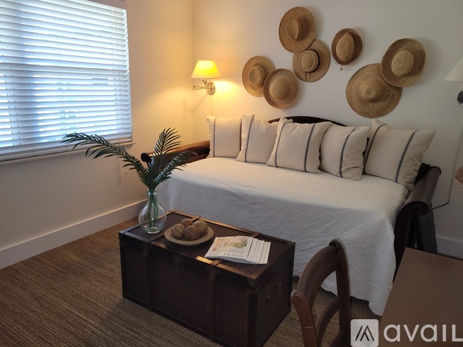 A bedroom with a bed, a table with a plant, and a wall decorated with hat-shaped decorations.