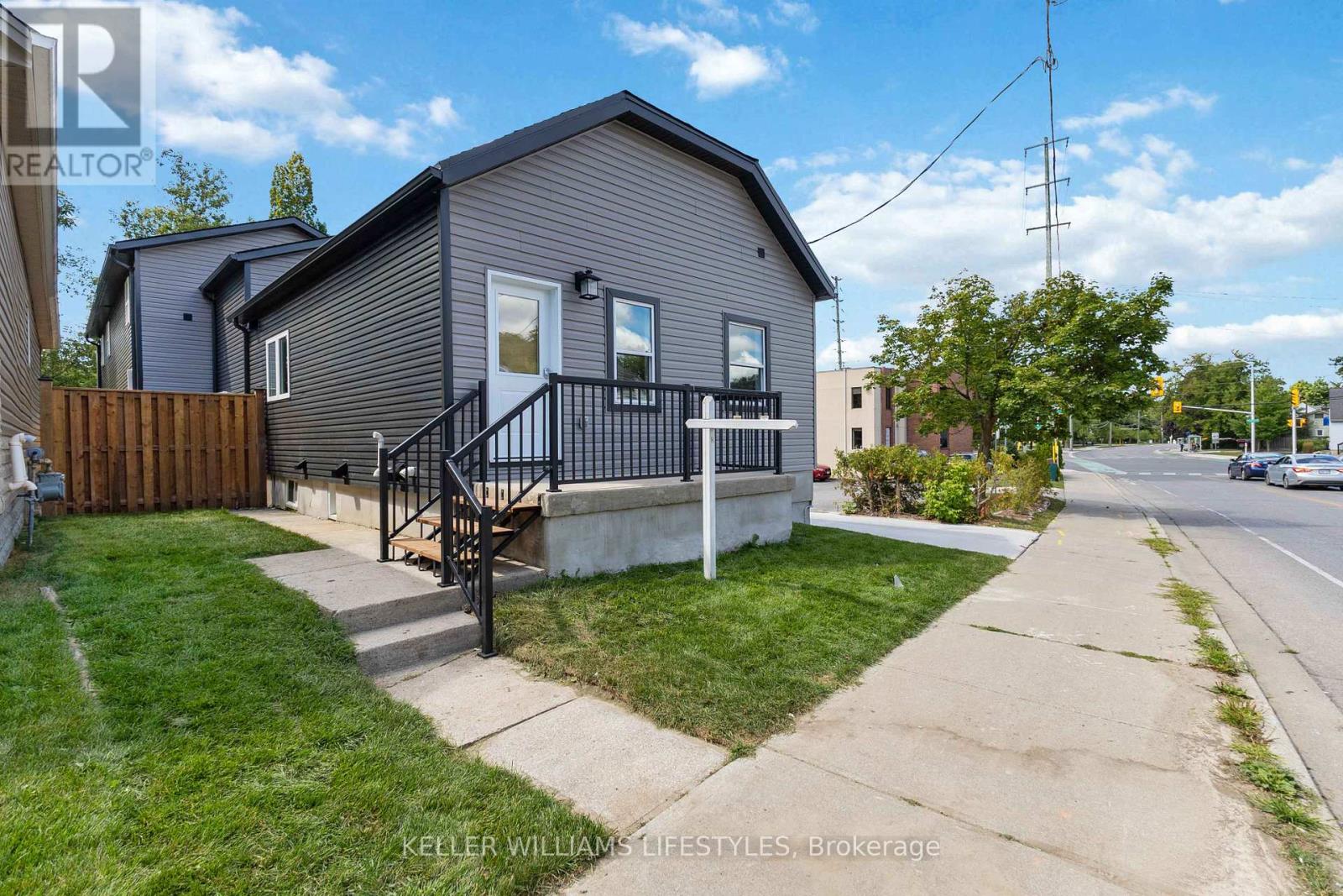 A grey house with a black railing on the front porch.