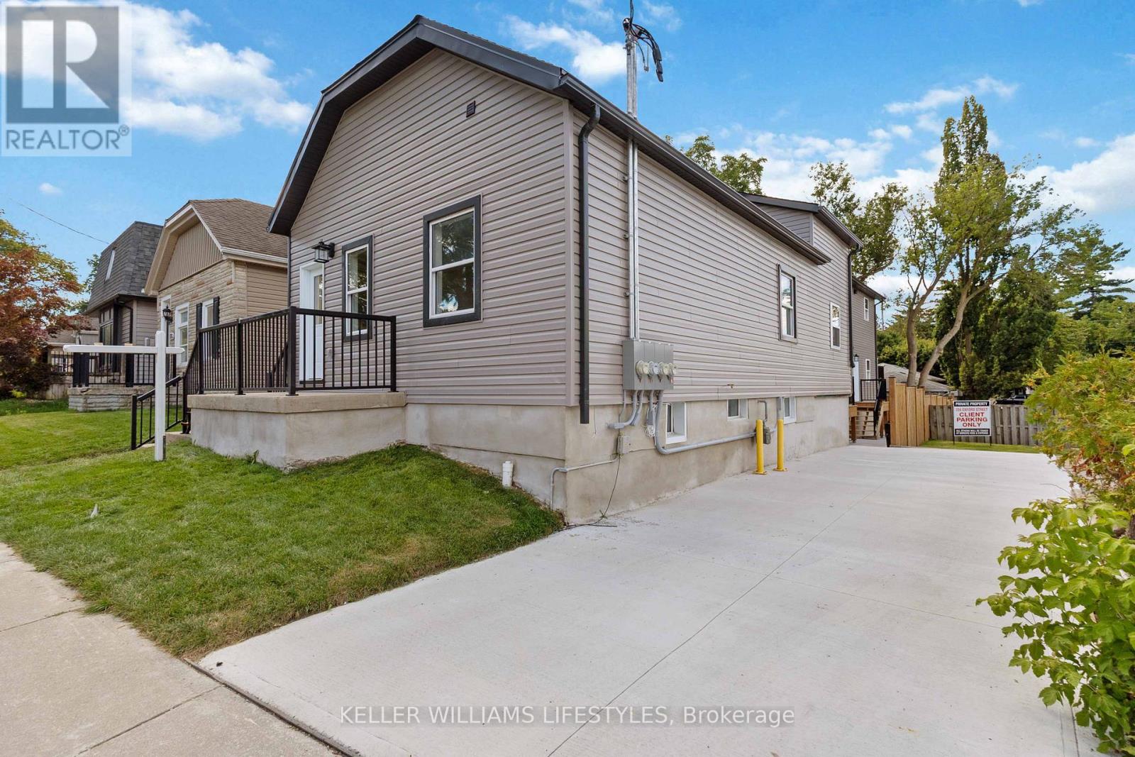 A realtor photo of a house with a driveway and a fence.