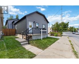 A grey house with a black railing on the front porch.