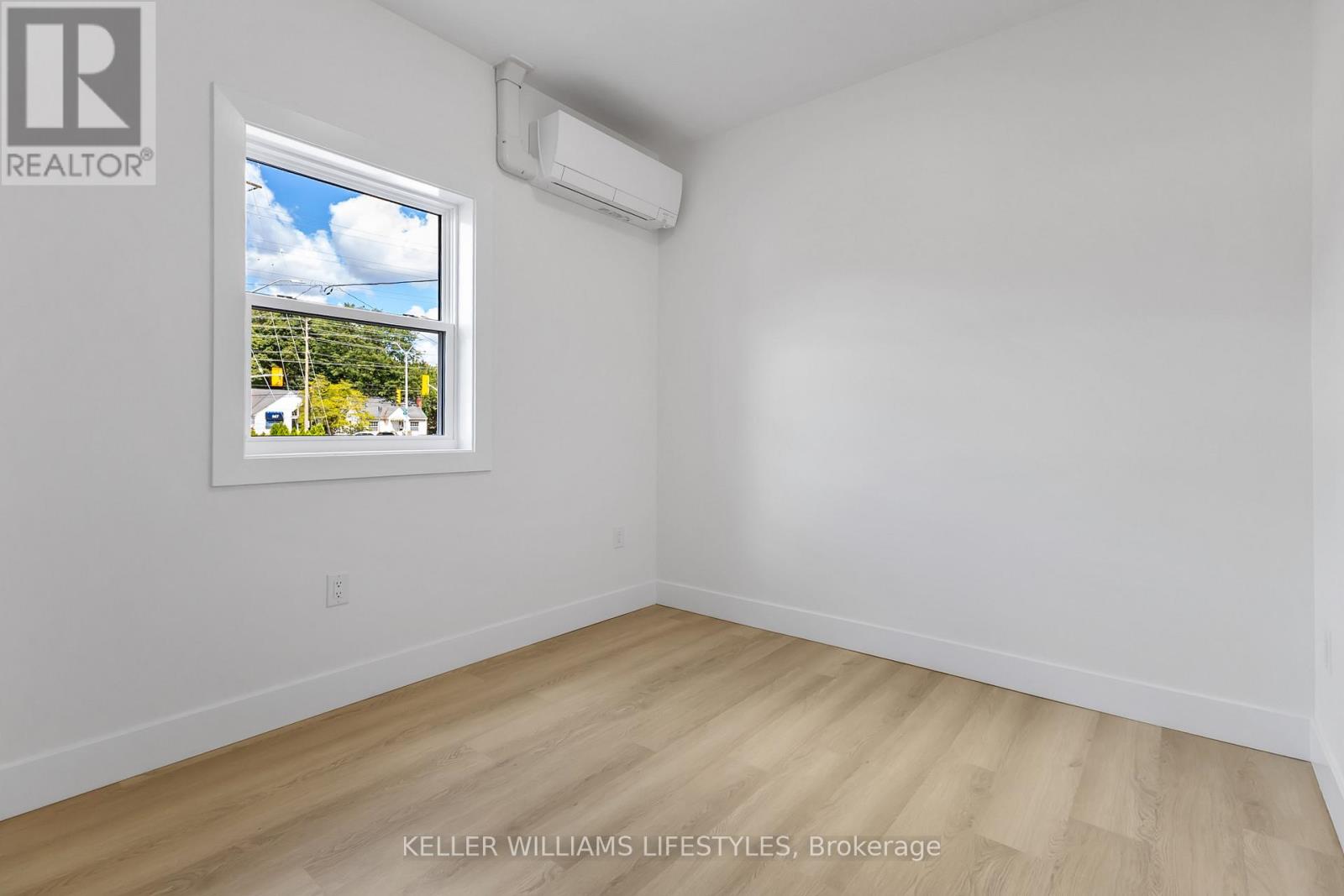 A room with a window showing a view of trees and houses outside.