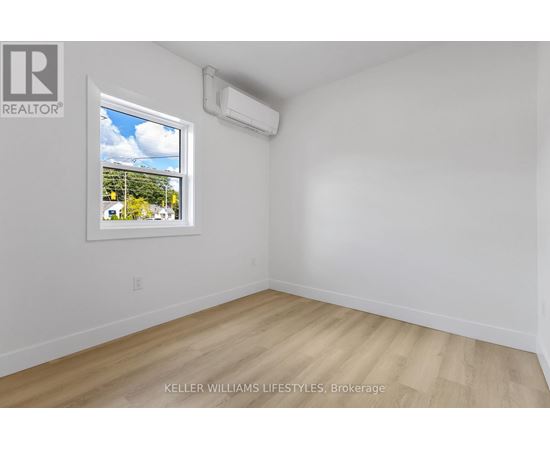 A room with a window showing a view of trees and houses outside.