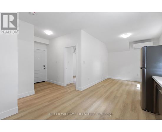 A kitchen area with a refrigerator and wooden flooring.