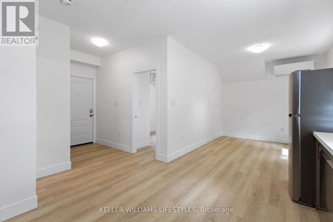 A kitchen area with a refrigerator and wooden flooring.