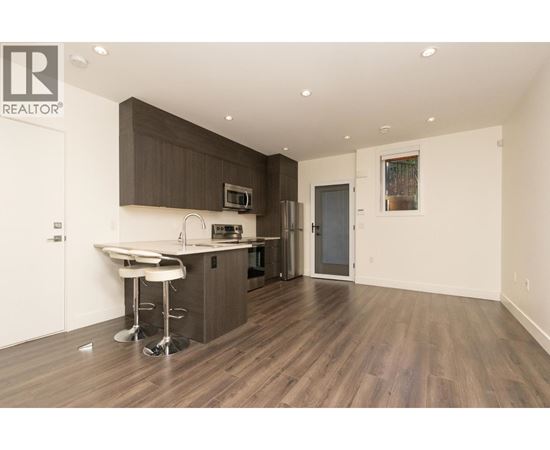 A modern kitchen with dark brown cabinets and white countertops.
