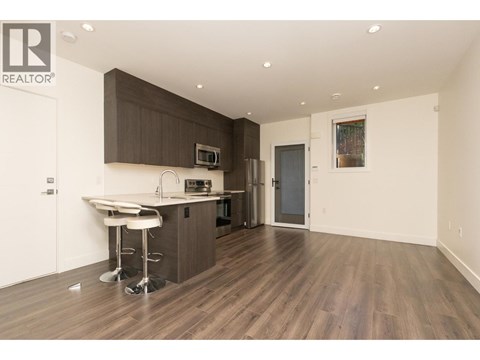 A modern kitchen with dark brown cabinets and white countertops.